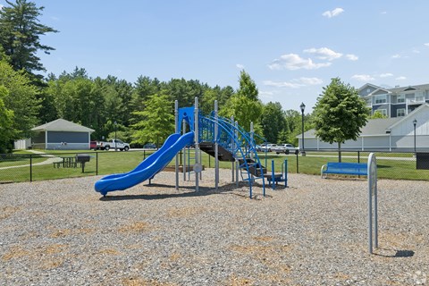 A playground with a blue slide and a grey gravel ground.
