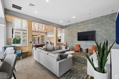 A living room with a grey couch and a television on the wall.