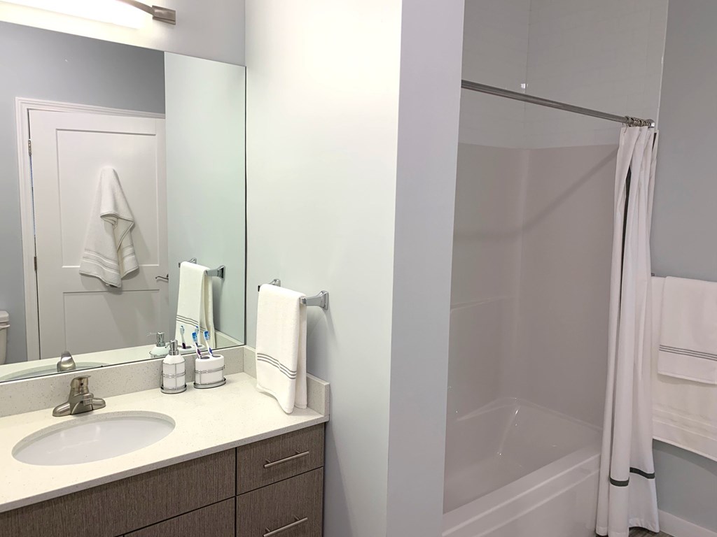 A bathroom with a sink, mirror, and shower.