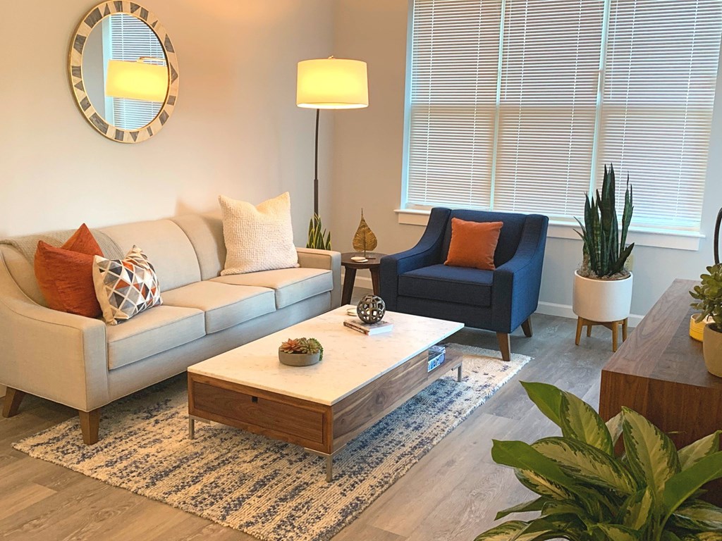 A living room with a white couch, a blue chair, and a wooden coffee table.
