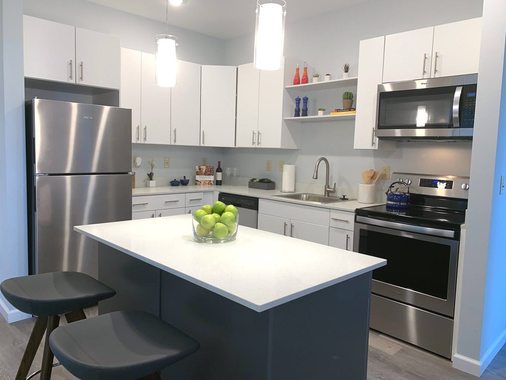 A kitchen with a white countertop and a bowl of green apples on it.