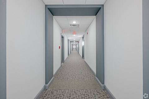 A long hallway with a carpeted floor and white walls.