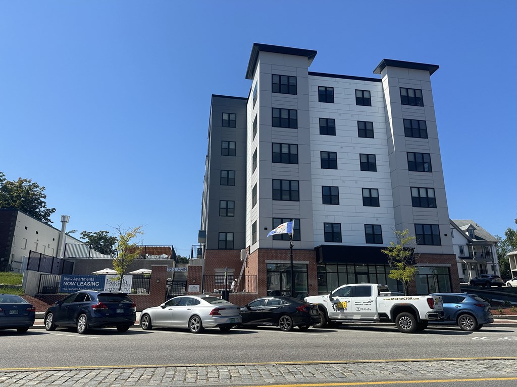 a tall building with cars parked in front of it on a city street