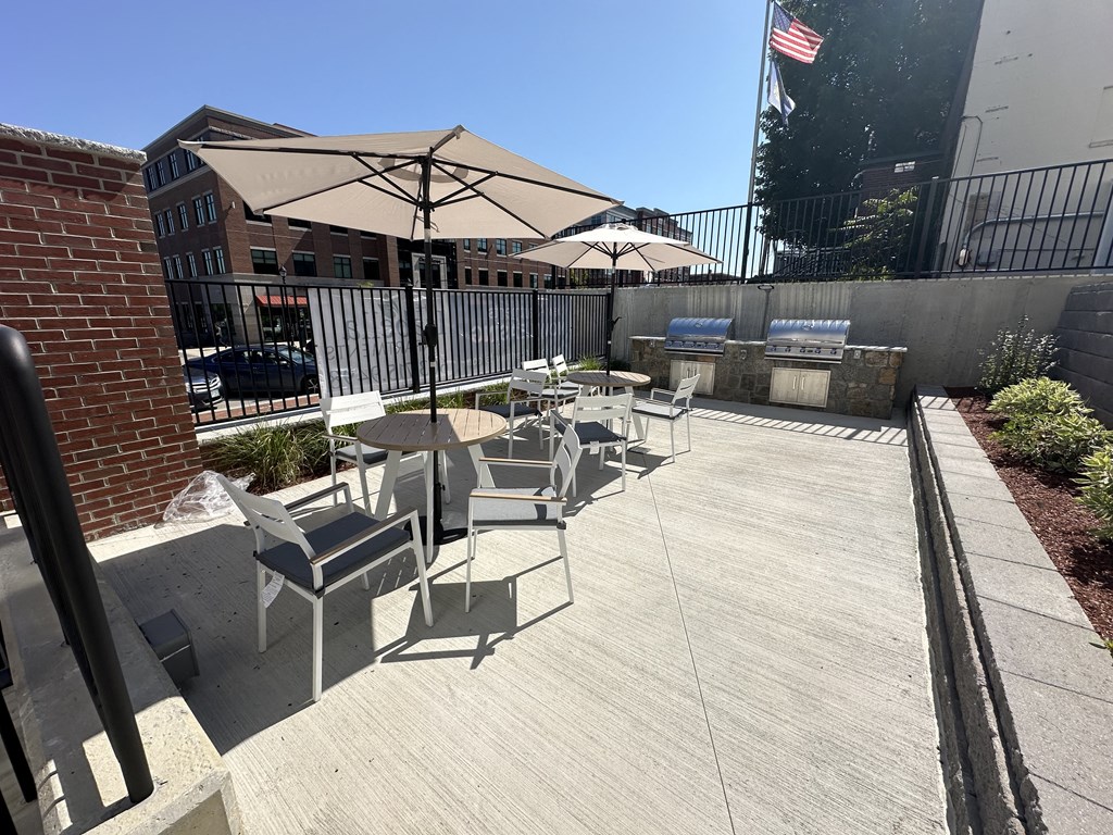 a patio with tables and umbrellas on top of a building
