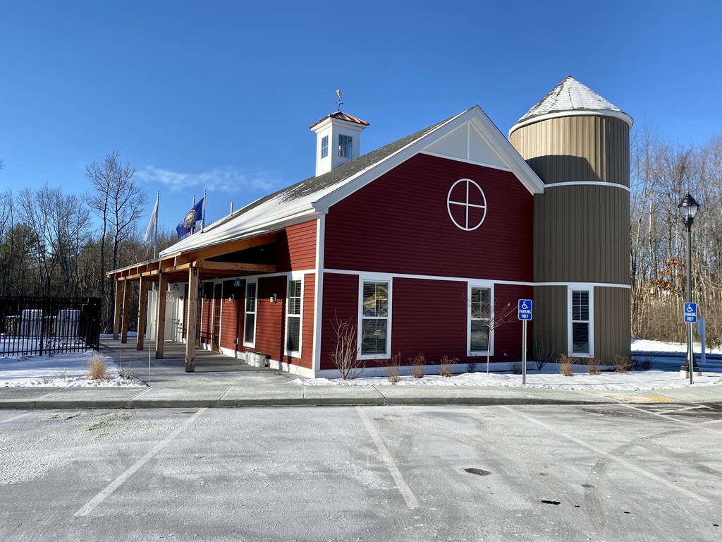 a red barn with a silo and a parking lot