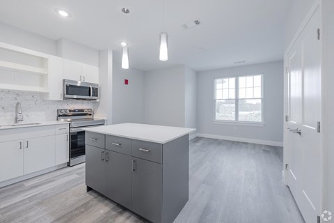 A kitchen with a white counter top and grey cabinets.