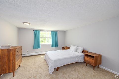 A bedroom with a bed, nightstand, and dresser.