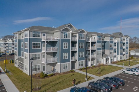 a large blue apartment building with cars parked in a parking lot