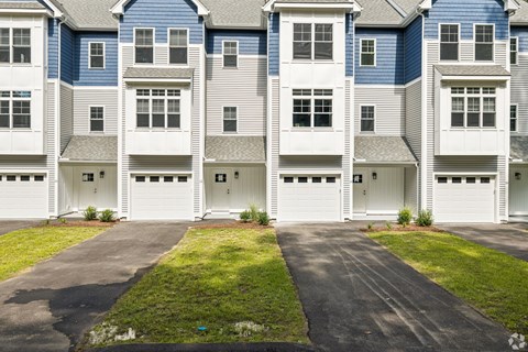 Apartment building with white garage doors and green grass.