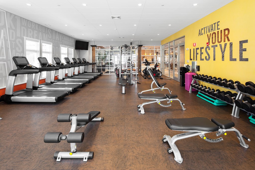 a gym with cardio equipment and weights on a wooden floor
