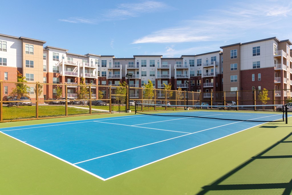 a tennis court with apartments in the background