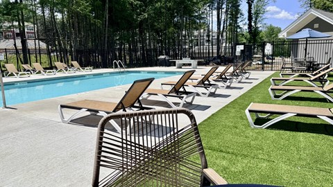 A poolside area with chairs and a table.