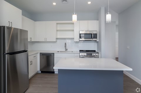 A modern kitchen with a stainless steel refrigerator and white countertops.