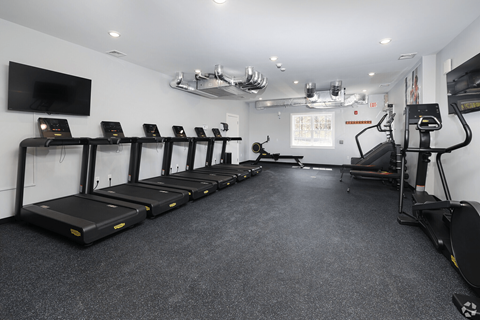 A gym with treadmills and a television on the wall.
