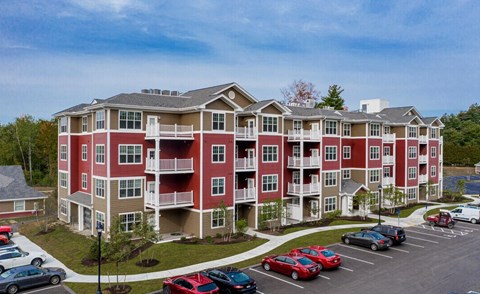 A large apartment complex with a parking lot in front.