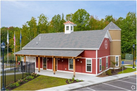 A red building with a white steeple and a black fence in front.