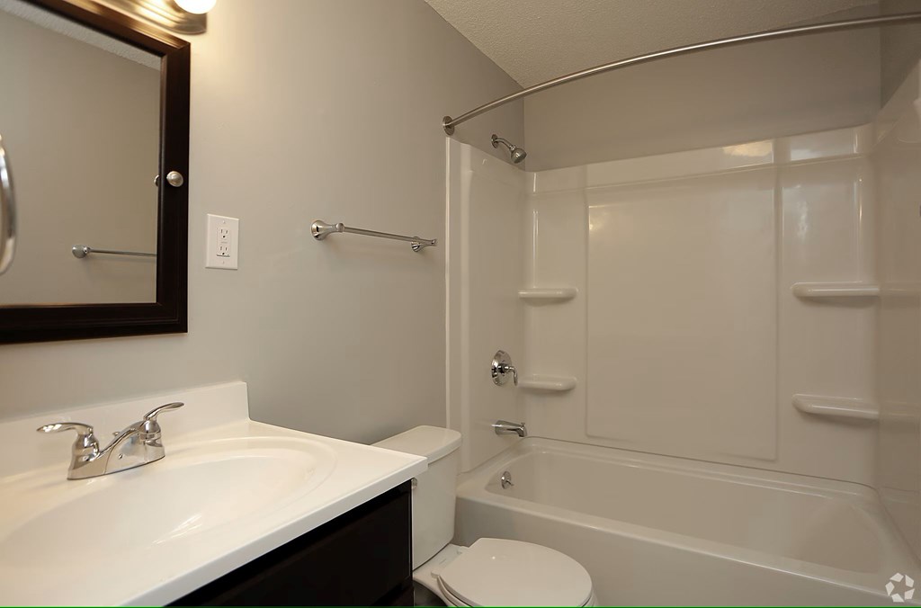 A white sink with a mirror above it and a white toilet in a bathroom.