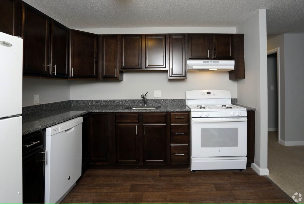 A kitchen with white appliances and brown cabinets.