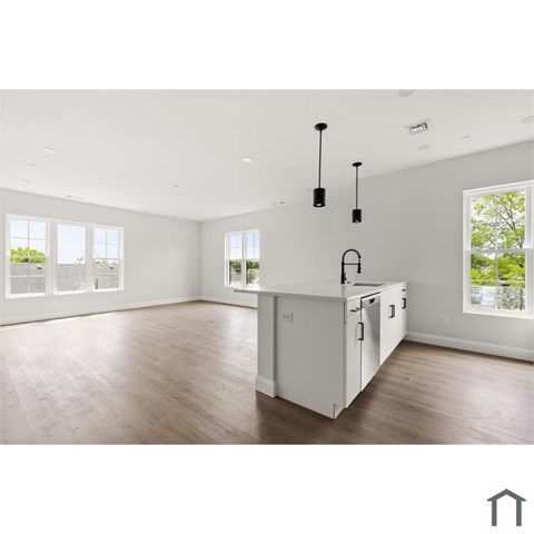 A kitchen with white cabinets and a wooden floor.