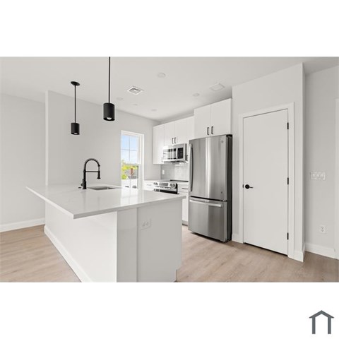 A modern kitchen with a white countertop and stainless steel appliances.
