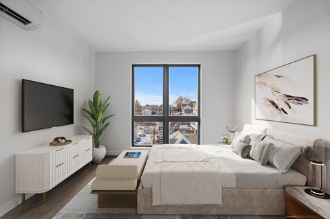 A bedroom with a large bed, a flat screen TV, and a window with a view of the city.