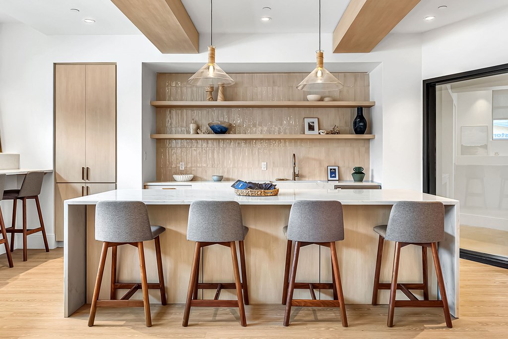 A modern kitchen with a bar area featuring a white countertop and grey barstools.