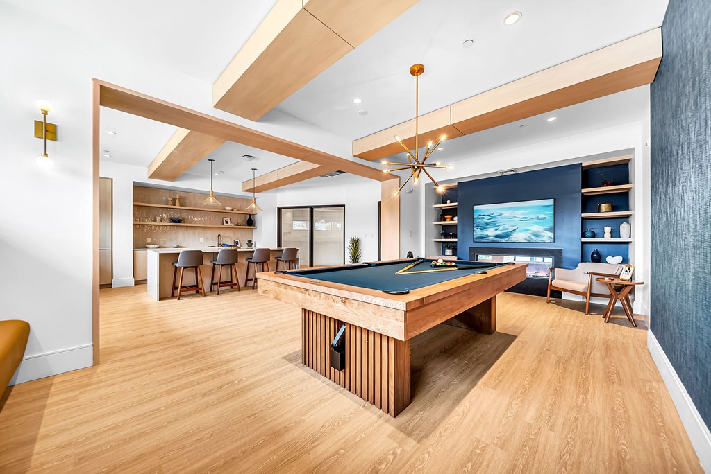 A billiard table is in the middle of a room with a wooden floor.