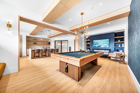 A billiard table is in the middle of a room with a wooden floor.