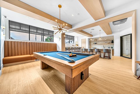 A billiard table in a room with wooden floors and a ceiling fan.