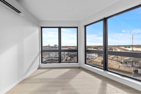 A room with a large window overlooking a parking lot and buildings.