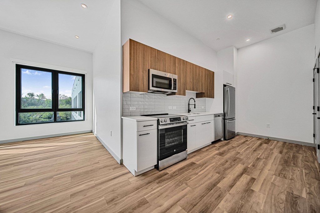 A modern kitchen with wooden floors and white appliances.
