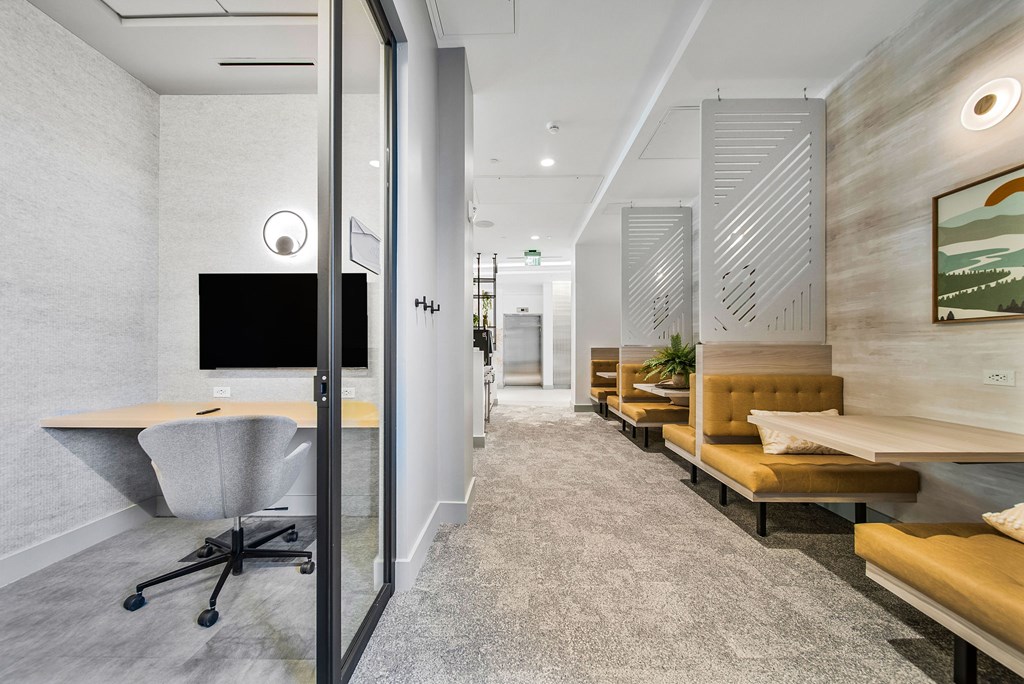 A modern office space with a long hallway, a desk with a computer, and a couch.
