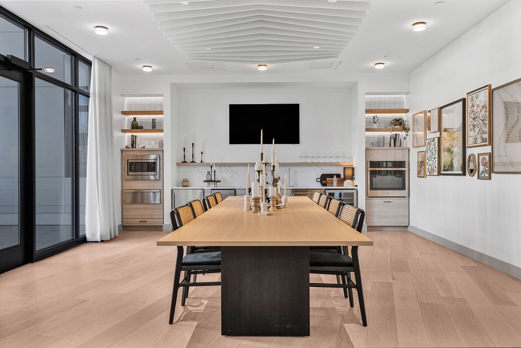 A modern dining room with a long wooden table and chairs.