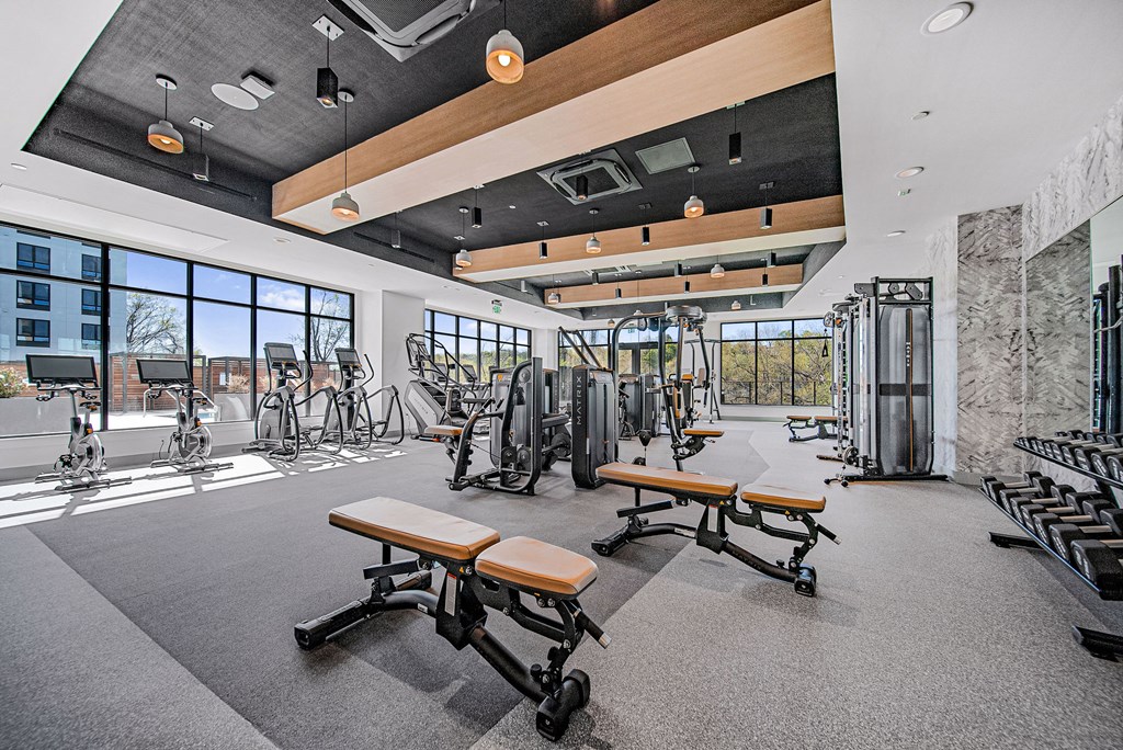 A gym with a variety of equipment including treadmills, weights, and exercise bikes.
