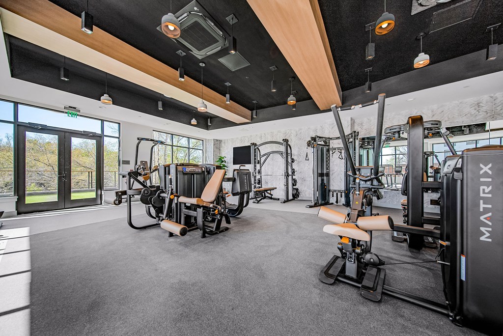 A gym with a variety of equipment including a squat rack, a leg press machine, and a bench press.