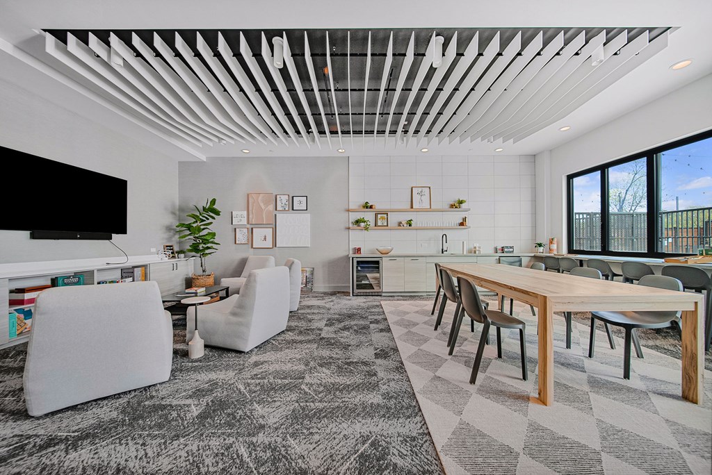 A modern living room with a long wooden table and white chairs.