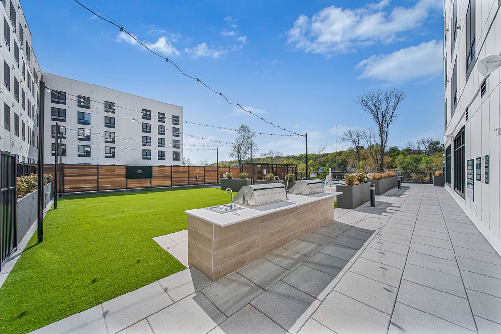 A modern outdoor kitchen area with a barbecue grill and a sink.