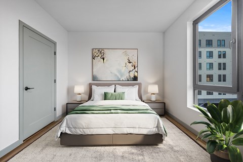 A bedroom with a large bed and a view of a building outside the window.