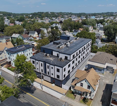 A large building with a black roof is in the center of a residential area.