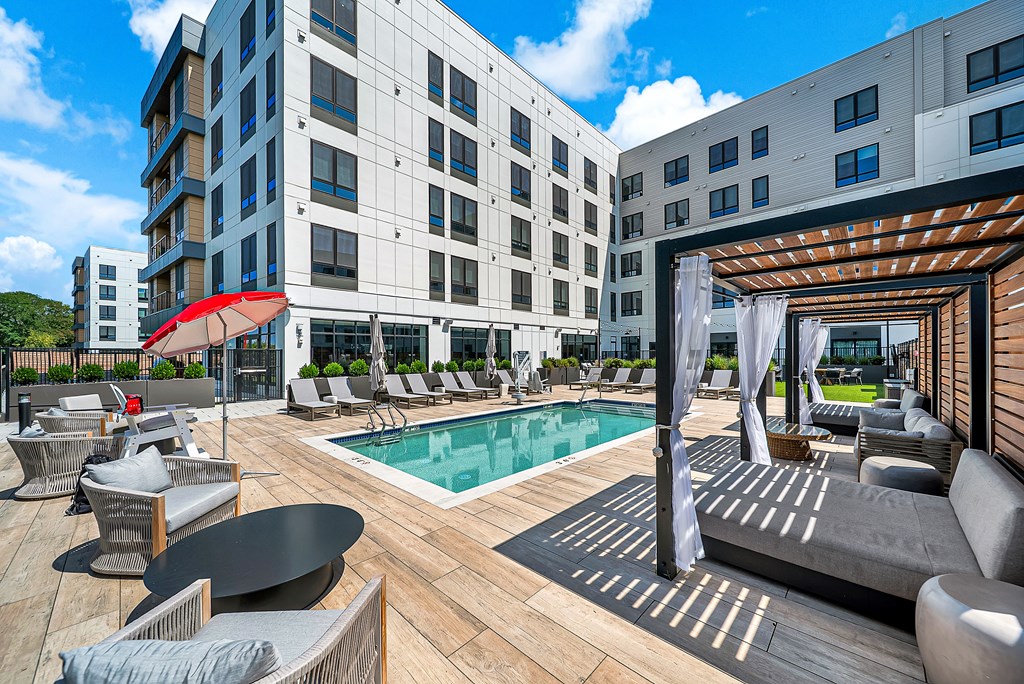 A modern outdoor pool area with a wooden deck and lounge chairs.