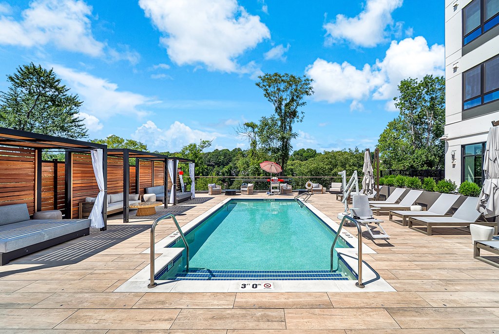 A swimming pool surrounded by lounge chairs and umbrellas.