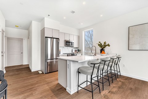 A kitchen with a white counter and bar stools.