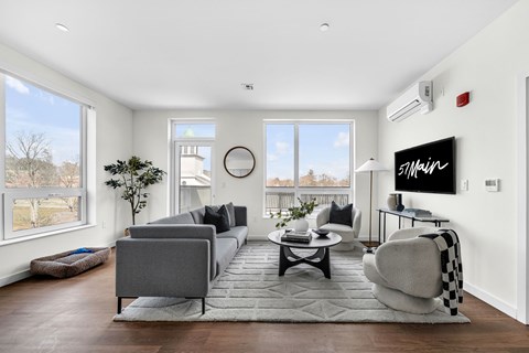 A modern living room with a grey sofa and a black and white checkered chair.