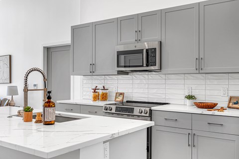A kitchen with white cabinets and a white countertop.