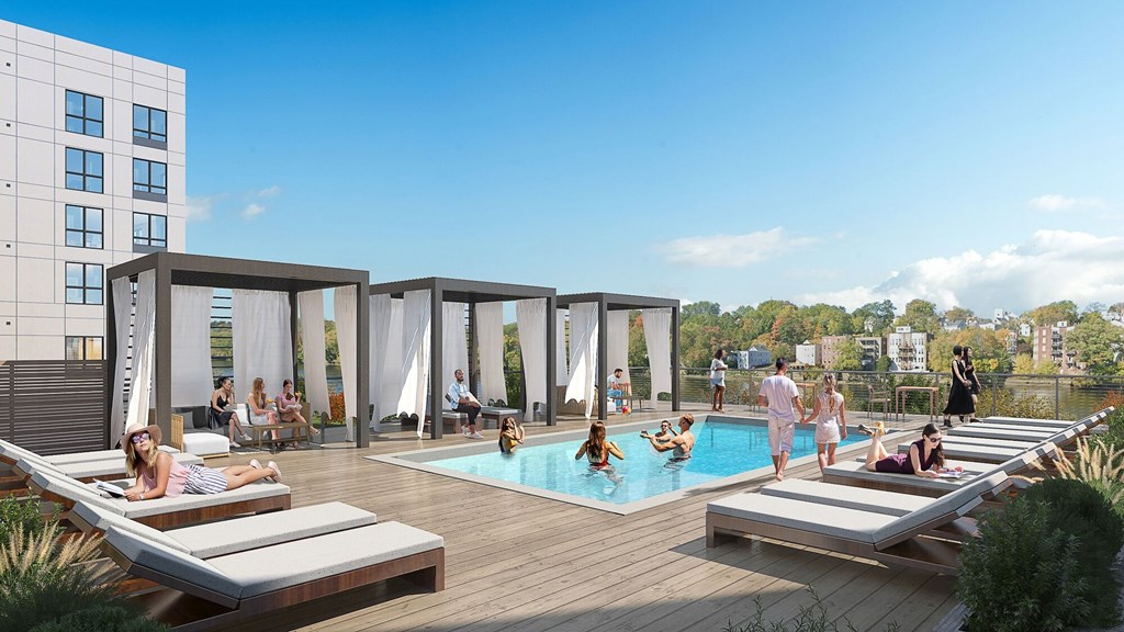 People are relaxing on sun loungers by a pool on a sunny day.