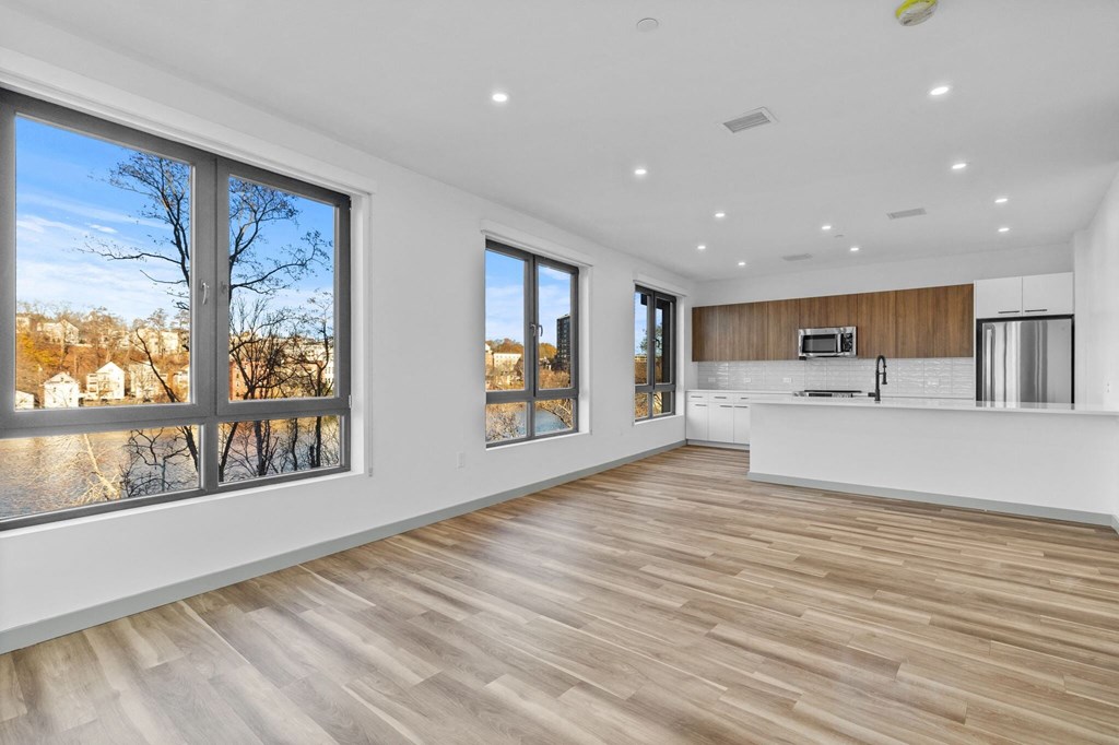 A spacious kitchen and living room with wooden floors and large windows.