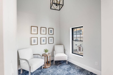 a living room with two white chairs and a window