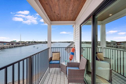 a view of the water from a balcony with chairs and a couch