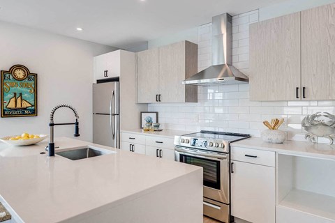a white kitchen with a large island and stainless steel appliances