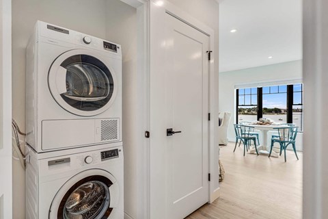 a front loading washer and dryer in a white laundry room with a door
